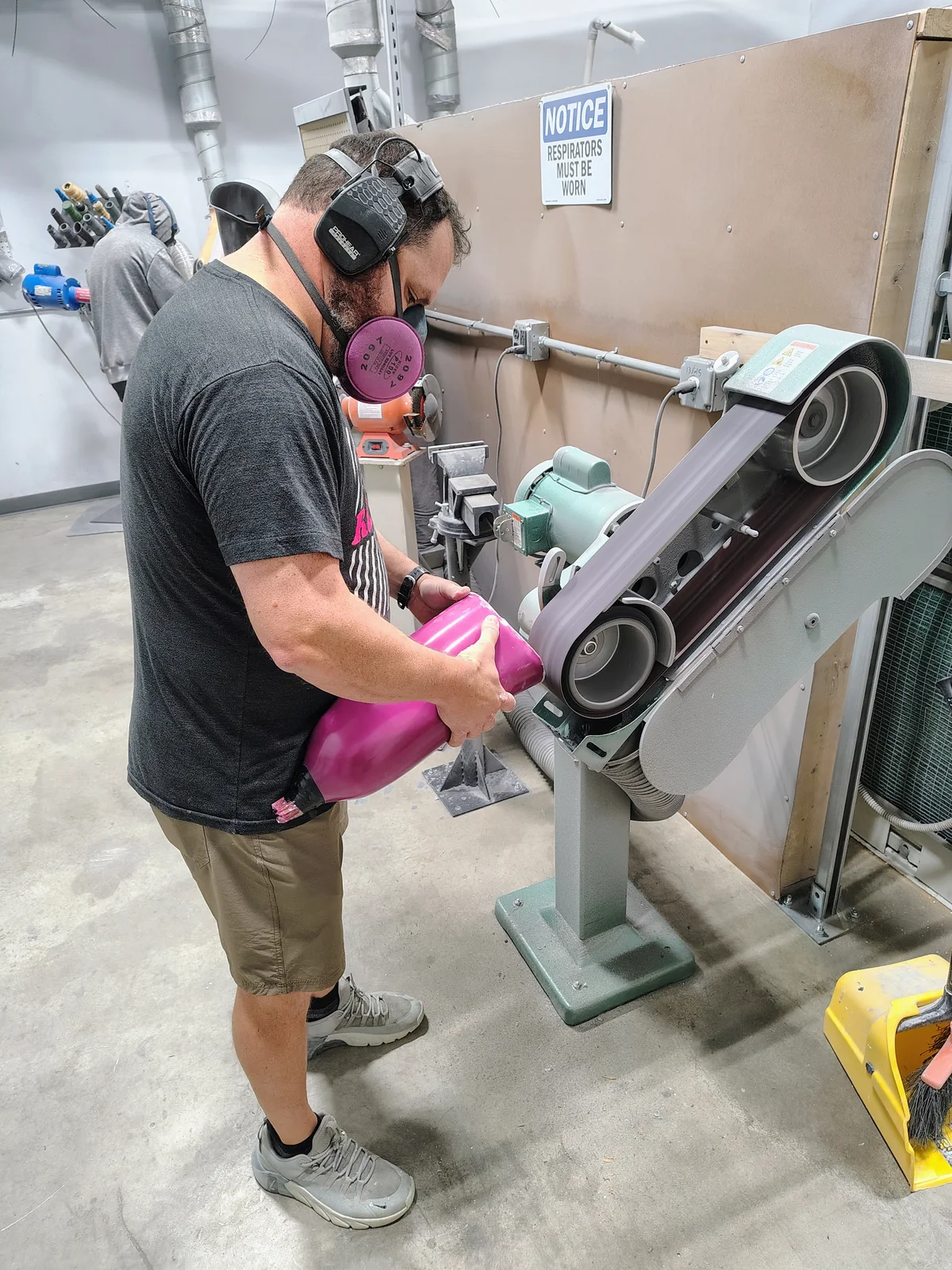 A FabCo technician smoothing a prosthetic socket on a belt sander