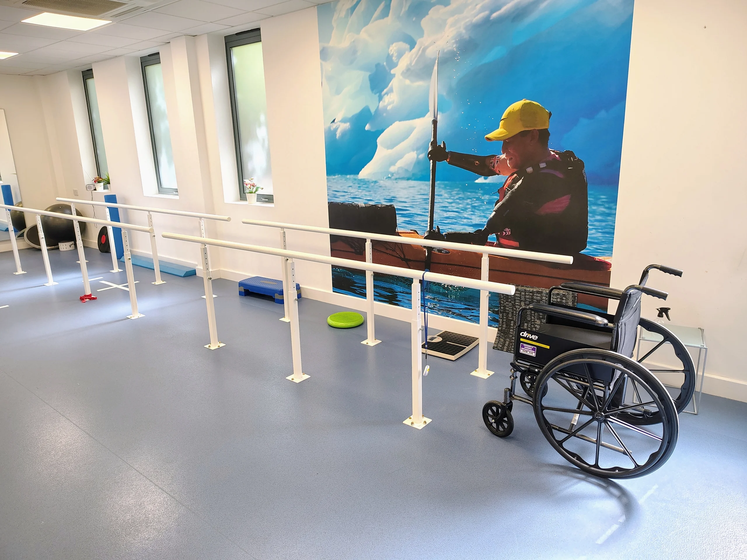 Parallel bars, a wheelchair and a wall mirror in the clinic’s gait-training area.