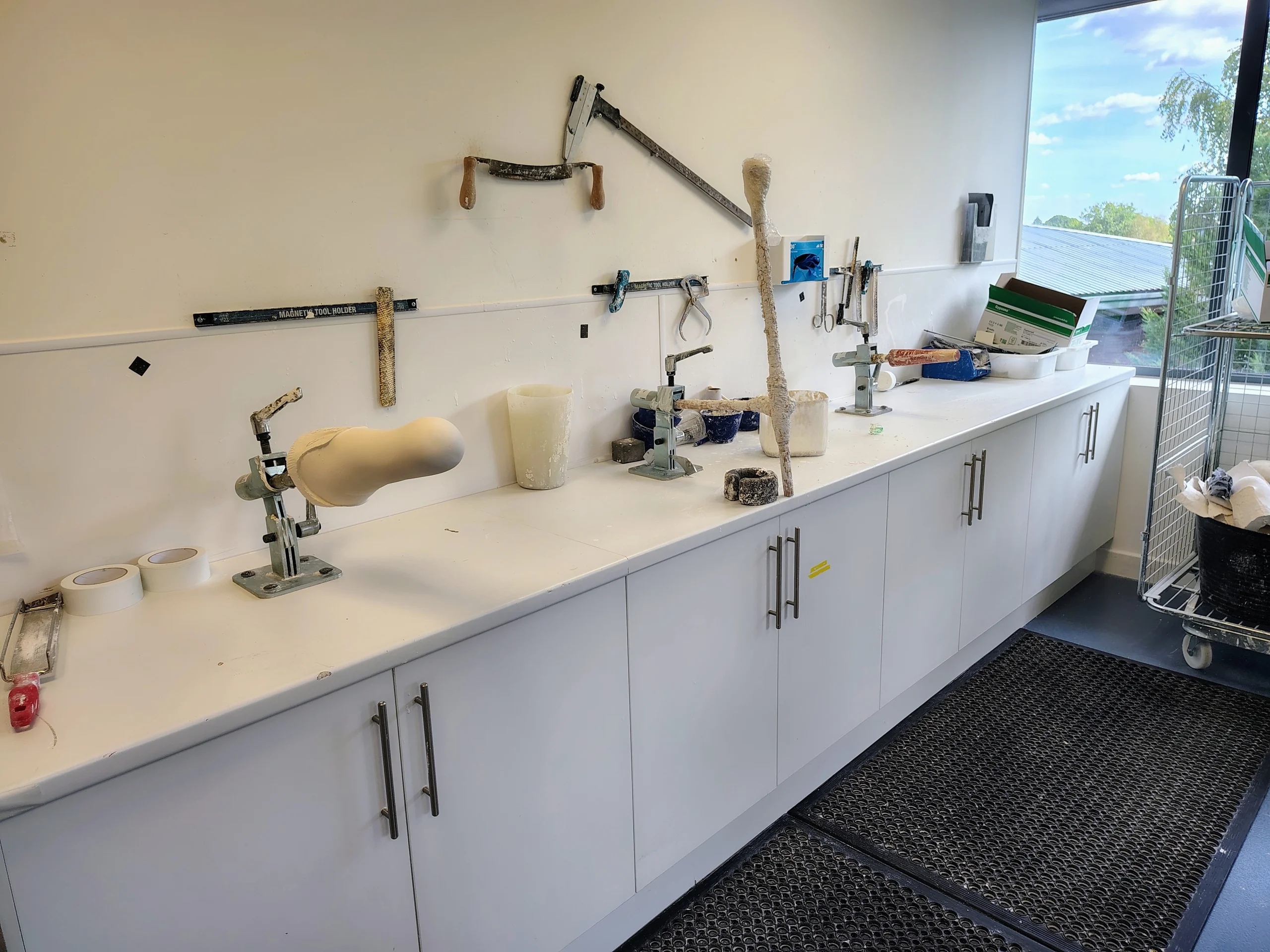 Plaster models mounted along a workbench with sinks and tools in the Amersham workshop.